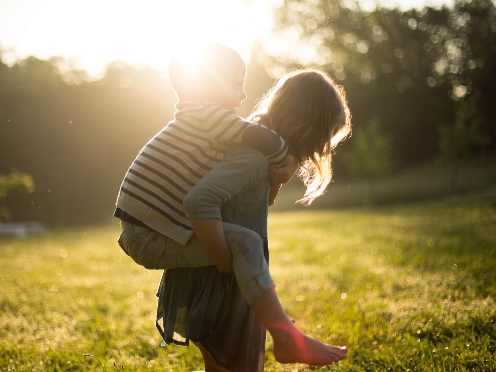 Kind wird huckepack getragen im Sonnenlicht